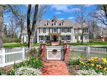 Charming two-story home with a white picket fence, brick pathway, and manicured landscaping at 4682 S Franklin St, Englewood, CO 80113