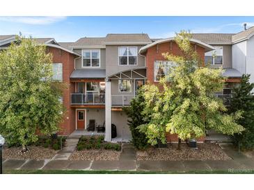Exterior of townhome featuring a balcony and landscaped front yard with mature trees and manicured grass at 85 Uinta Way # 603, Denver, CO 80230