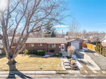 Charming brick home with a spacious front yard and detached garage on a sunny day at 6719 Quay St, Arvada, CO 80003