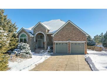 Brick home with two-car garage and snow-covered landscaping at 1430 Milbury St, Castle Rock, CO 80104