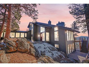 Beautiful two-story home with large windows, set amongst the trees with a rocky landscape at 1692 Sand Lily Dr, Golden, CO 80401