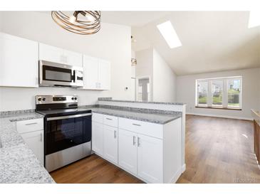 Modern kitchen with stainless steel appliances, granite countertops, and a breakfast bar at 7722 S Steele St, Centennial, CO 80122