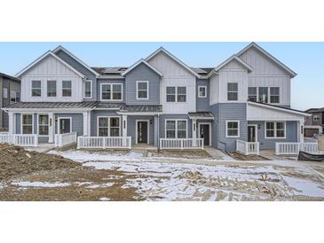 Three-unit townhome building with gray siding, white trim, and front porches at 14556 W 91St Ave # A, Arvada, CO 80005