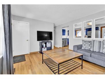 Bright living room featuring hardwood floors, modern decor, and an open view to the kitchen at 6434 S Dudley Way, Littleton, CO 80123