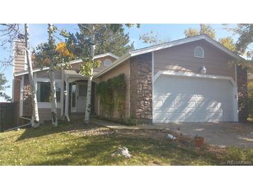 Tan house with stone accents, white garage door, and landscaping at 2750 S Rifle St, Aurora, CO 80013