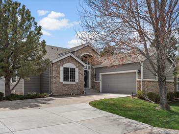 Charming home featuring a stone facade, inviting entrance, manicured lawn and a two-car garage with ample driveway parking at 7400 W Grant Ranch Blvd # 5, Littleton, CO 80123