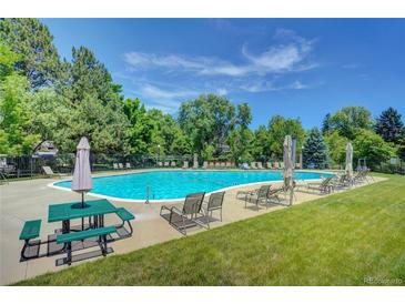Large community swimming pool with picnic table, lounge chairs and umbrellas at 5050 W 102Nd Ave, Westminster, CO 80031