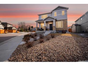 Charming two-story home with stone accents and a beautifully landscaped front yard at sunset at 11650 Park South Ln, Parker, CO 80138