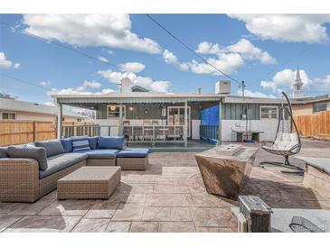 Spacious backyard patio with comfortable seating area, fire pit, and unique hanging chair at 6190 Garrison St, Arvada, CO 80004