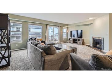 Comfortable living room with a stone fireplace, plush seating, and large windows for natural light at 6250 Everett Ct # F, Arvada, CO 80004