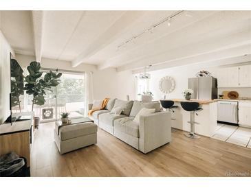 Bright living space featuring a comfortable gray sofa, wood floors, and access to a balcony at 1365 Columbine St # 204, Denver, CO 80206