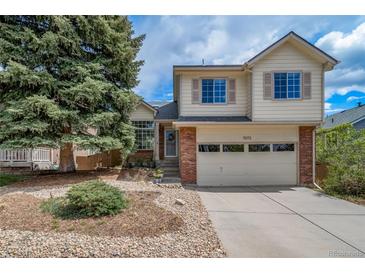Inviting two-story home with brick accents, large tree, and well-maintained front yard and two car garage at 7072 Palisade Dr, Highlands Ranch, CO 80130