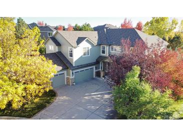 Landscaped two-story home featuring a three-car garage and colorful fall foliage at 22386 E Arbor Pl, Aurora, CO 80016