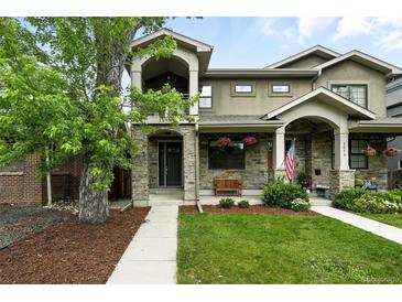 Charming two-story home with stone accents, a covered porch, landscaped yard, and a mature tree in front at 2077 S Clayton St, Denver, CO 80210