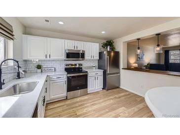 Well-lit kitchen featuring white cabinets, stainless steel appliances, and breakfast nook access at 7822 S Kittredge Cir, Englewood, CO 80112