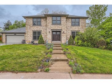 Inviting two-story brick home featuring a landscaped front yard and charming architectural details at 8075 S Harrison Way, Centennial, CO 80122