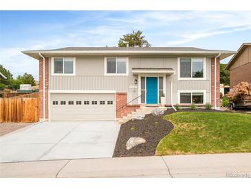 Charming two-story home featuring a blue front door, brick accents, and a well-manicured front yard at 2027 S Welch Cir, Lakewood, CO 80228