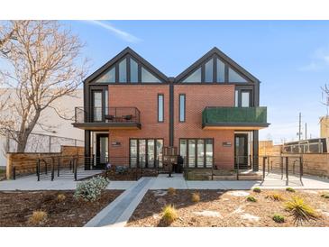 Modern townhome with a brick facade, black accents, balconies, and landscaping, under a clear blue sky at 4232 Jason St # 2, Denver, CO 80211