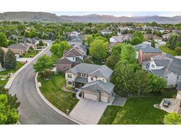 Beautiful aerial view of a suburban home with a well-manicured lawn and a tree-lined street surrounded by lush greenery at 5683 Fig Way, Arvada, CO 80002