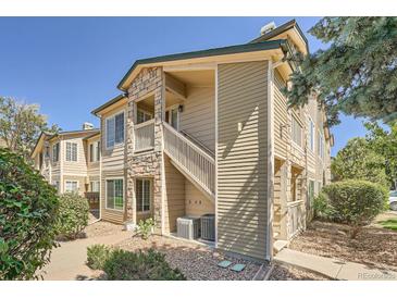 Tan two-story condo building with stone accents and a stairway at 9963 E Carolina Cir # 202, Aurora, CO 80247