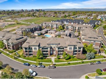 Stunning aerial view of a condo community with lush landscaping, pool, and city skyline in the background at 3865 S Dayton St # 105, Aurora, CO 80014
