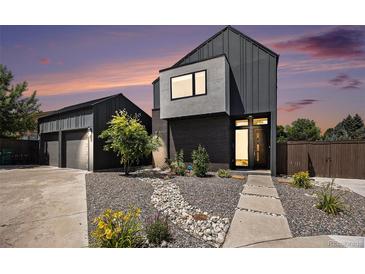Modern home featuring dark siding, a landscaped yard with a rock pathway, and a detached garage at 3057 S University Cir, Englewood, CO 80113