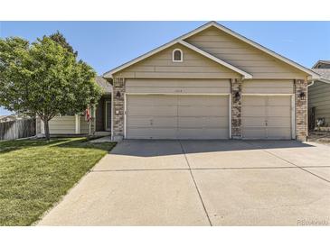 Charming home featuring a three-car garage, well-maintained lawn, mature tree, and neutral-toned exterior at 11014 Callaway Rd, Parker, CO 80138
