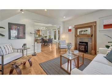 Bright living room featuring hardwood floors, a decorative fireplace, and an open layout to the dining area at 1716 S Ogden St, Denver, CO 80210