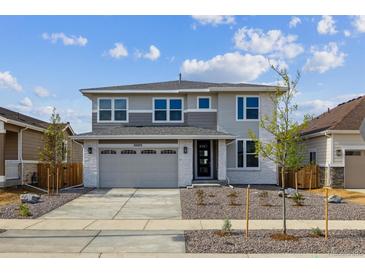 Beautiful two-story home with gray and white stone exterior, well-manicured front yard, and a two-car garage at 25273 E Warren Pl, Aurora, CO 80018