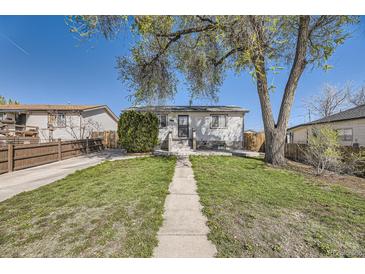 Charming home featuring a well-maintained front yard with mature tree and concrete walkway at 2448 S Galapago St, Denver, CO 80223