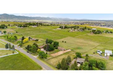 Expansive aerial view of acreage with lush green pastures, scattered trees and mountain views in the distance at 7583 W Trail South Dr, Littleton, CO 80125