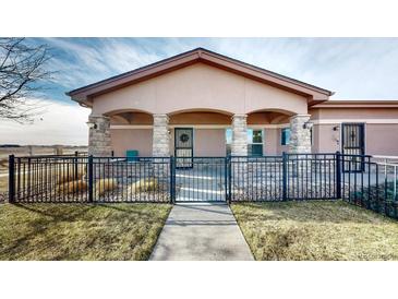 Charming home featuring a covered porch with stone pillars and black metal fencing at 15501 E 112Th Ave # 30A, Commerce City, CO 80022