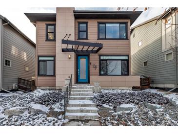 Contemporary two-story home featuring a covered entryway and a vibrant blue front door at 6715 Raritan Dr, Denver, CO 80221