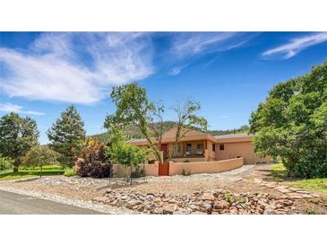 A charming single-story home boasts a unique exterior design with a stone landscape and well-kept lawn at 6201 Rain Dance Trl, Littleton, CO 80125