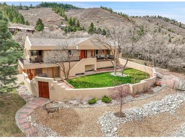 Stunning home with stucco walls, beautiful landscaping, and mature trees nestled in a hillside setting at 6201 Rain Dance Trl, Littleton, CO 80125