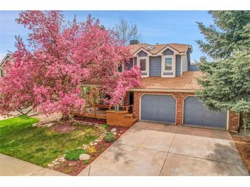 Charming two-story home with a beautiful blooming tree in the front yard and a two car garage at 12718 W 84Th Dr, Arvada, CO 80005