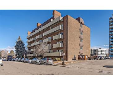 Brick apartment building featuring balconies and visible street parking in a vibrant urban setting at 4110 Hale Pkwy # 1E, Denver, CO 80220