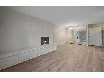 Bright living room with modern flooring, brick fireplace and mirrored closet doors at 4110 Hale Pkwy # 1E, Denver, CO 80220