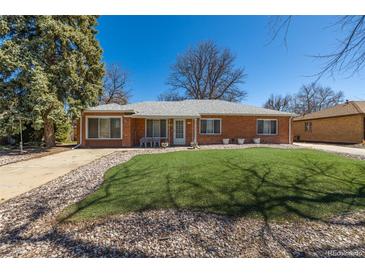 Charming brick home features a well-manicured lawn and classic architectural details at 938 Racine St, Aurora, CO 80011