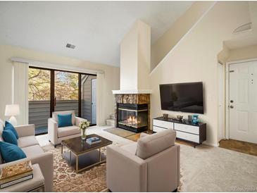 Inviting living room features a stone fireplace, plush seating, and sliding glass doors to the outdoors at 3600 S Pierce St # 5-204, Denver, CO 80235