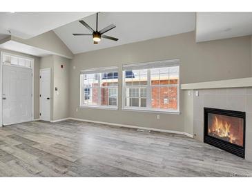 Bright living room with fireplace, ceiling fan, wood floors, and large windows at 14308 E Whitaker Pl # 114, Aurora, CO 80015