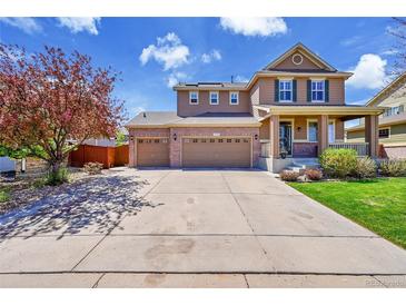 Inviting two-story home featuring a three-car garage, covered front porch, and well-maintained landscaping at 25262 E 2Nd Pl, Aurora, CO 80018