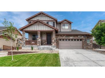 Charming two-story home featuring stone accents, a covered porch, a well-manicured lawn, and an attached two-car garage at 22583 E Union Cir, Aurora, CO 80015