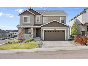 Charming two-story home featuring a two-car garage, well-maintained lawn, and inviting front porch with white railings at 2576 Villageview Ln, Castle Rock, CO 80104