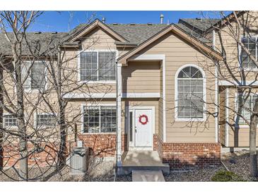 Charming townhome featuring beige siding, brick accents, and a welcoming front door with festive wreath at 6845 S Webster St # G, Littleton, CO 80128