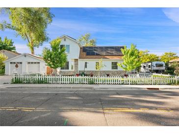 Charming two-story home featuring a white picket fence, solar panels, and a detached garage at 8501 W 52Nd Ave, Arvada, CO 80002