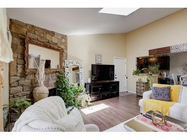 Bright living room with stone fireplace, skylight, and hardwood floors for a warm, inviting ambiance at 10150 E Virginia Ave # 18-302, Denver, CO 80247