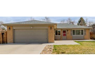 Charming brick home featuring a two-car garage, well-maintained lawn, and a welcoming front entrance at 396 Tucson St, Aurora, CO 80011