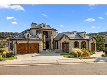 Stunning stone and stucco home with a charming courtyard, wooden garage doors and lush landscaping at 7912 Raphael Ln, Littleton, CO 80125