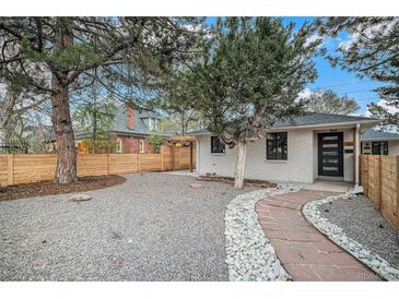 Charming home features a well-maintained front yard with beautiful landscaping, a quaint stone path, and privacy fencing at 1362 Wolff St, Denver, CO 80204